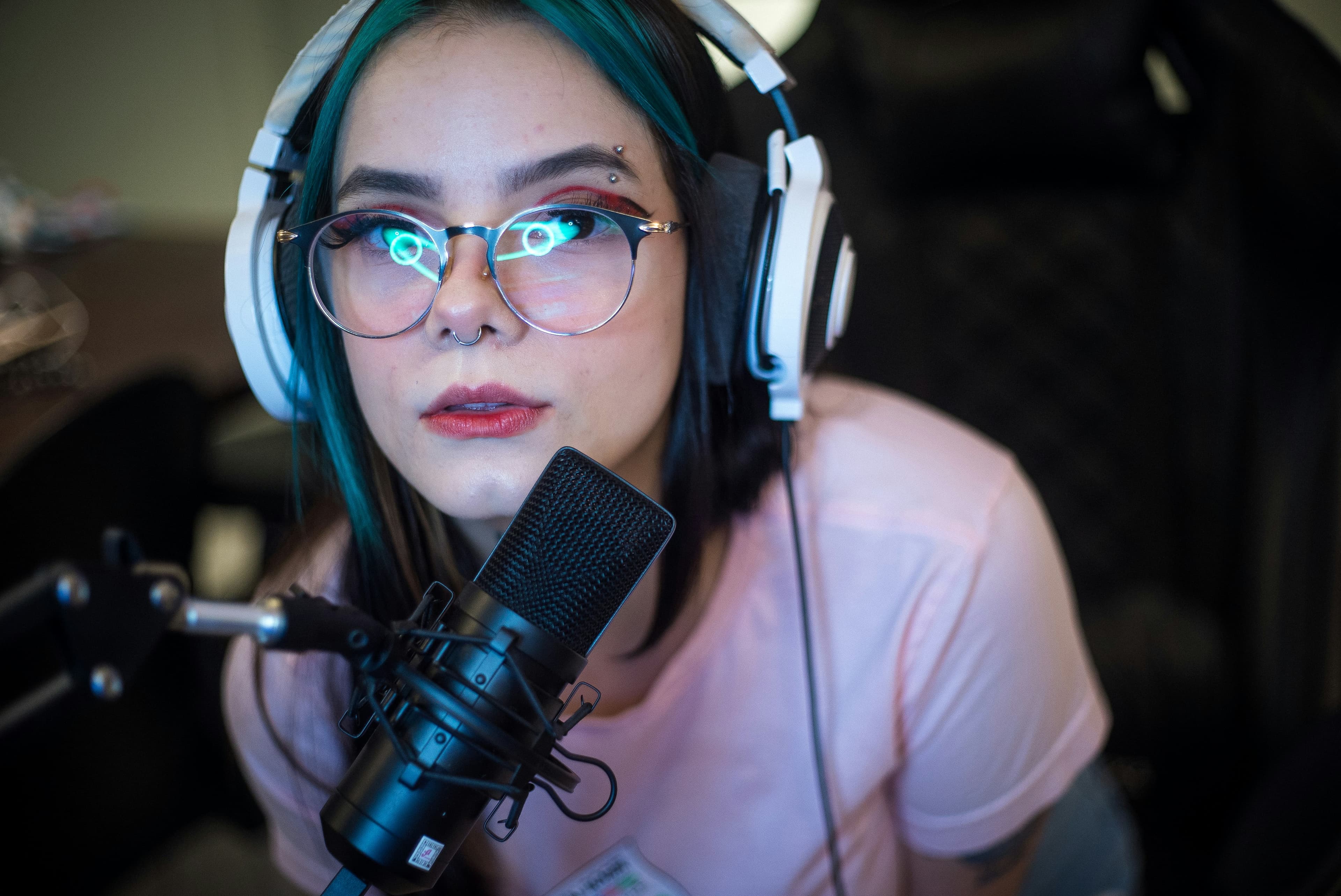 A confident creator wearing blue headphones and holding a microphone in a bright modern studio, ready to go LIVE.