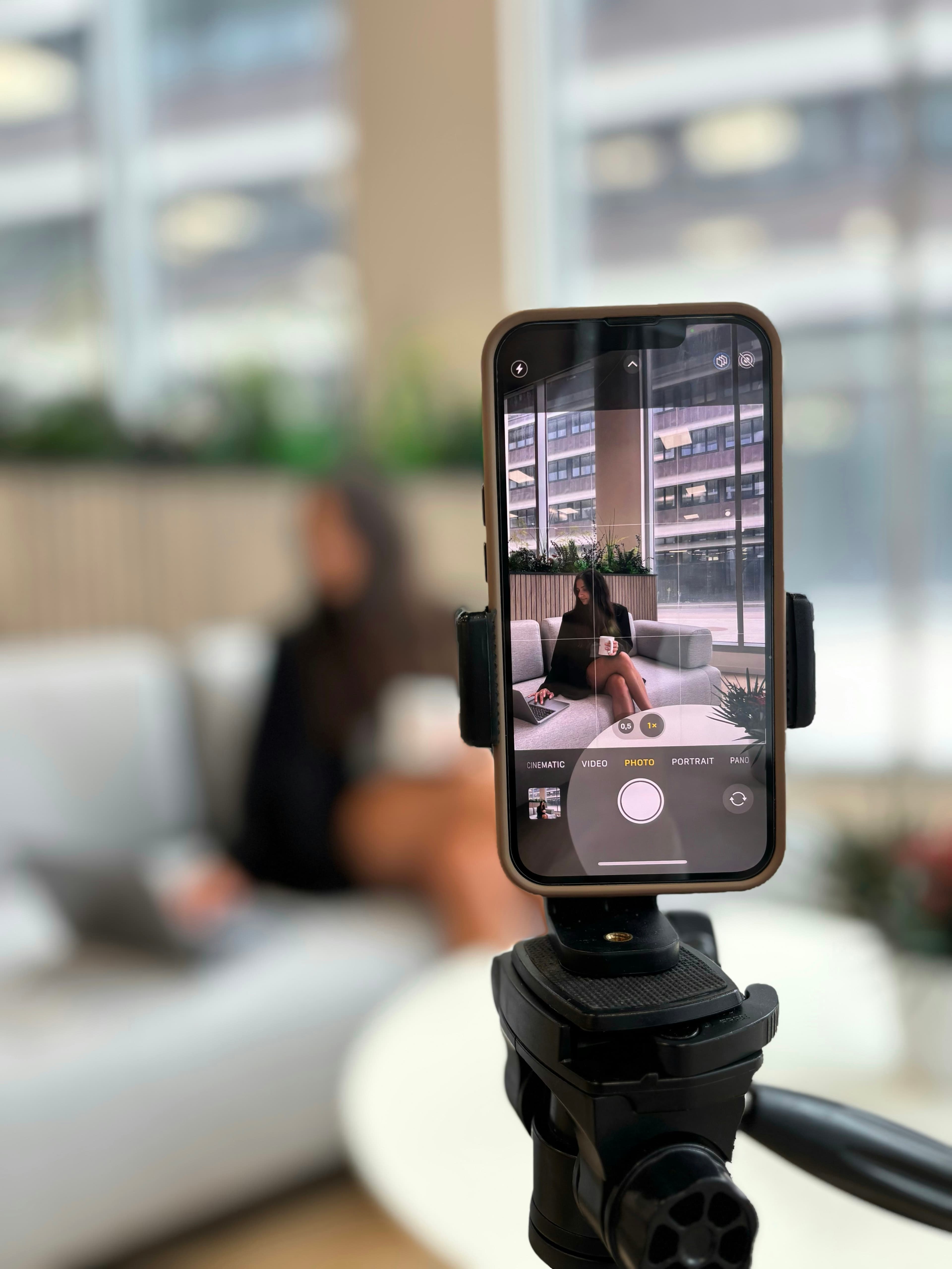 A creator recording content on a smartphone in a relaxed modern environment.