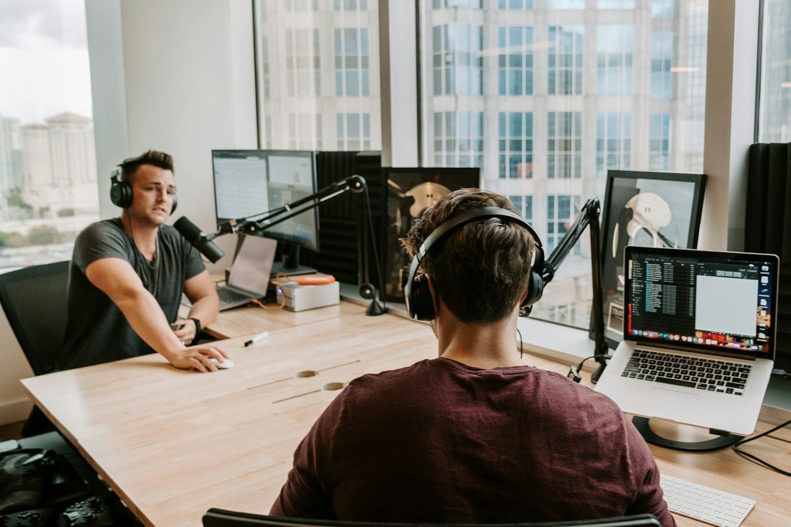 Two content creators recording together with professional microphones and headphones.